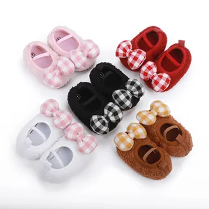 Vista dettagliata di scarpine primi passi in peluche per neonati con fiocchi a quadretti.