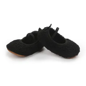 Close-up of fuzzy black baby Mary Janes with soft brown soles and elastic straps.