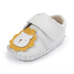 Détail d'une chaussure bébé blanche avec lion de dessin animé et attache velcro