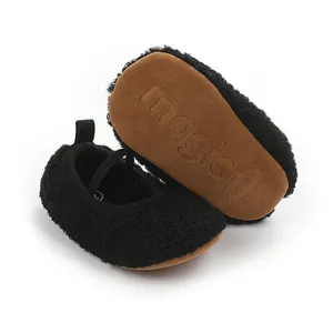 Macro detail of black fuzzy baby prewalker shoes with non-slip brown rubber soles