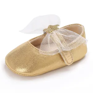 Detailansicht eines glänzenden goldenen Baby-Prinzessinenschuhs mit weißer Netzschleife