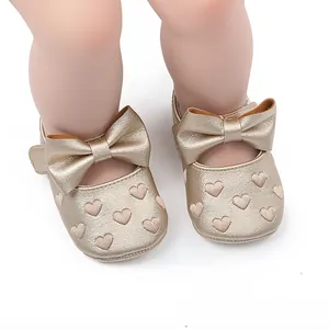 Detailansicht goldener Baby-Prinzessinnen-Lauflernschuhe mit Schleife und Stickerei-Herzen
