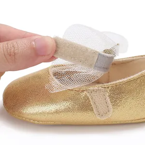 Nahaufnahme des verstellbaren Klettverschlusses an goldenen Baby-Prinzessinnenschuhen