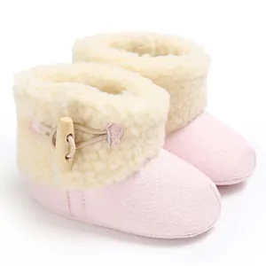 Primer plano de botas de nieve rosa para bebé con forro de pelo sintético y botón