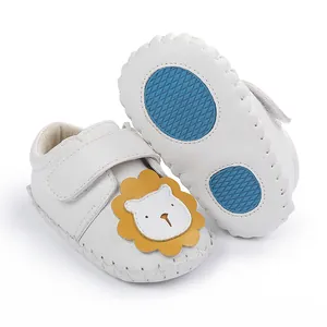Vue détaillée de chaussures blanches pour bébé avec lion et semelles antidérapantes