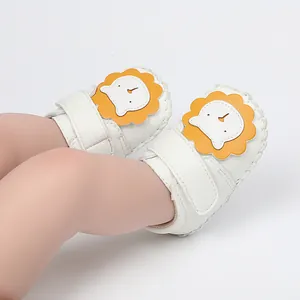 Détail rapproché de jolies chaussures bébé premier pas blanches avec motif lion jaune
