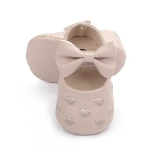 Detailansicht der Herzstickerei und der großen Schleife an rosa Baby-Prinzessinnen-Schuhen