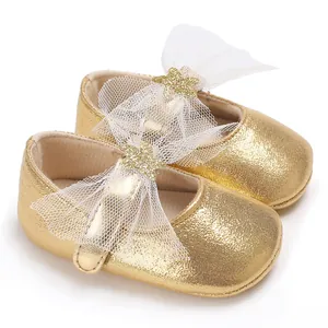 Detailansicht goldener Glitzer-Babyschuhe mit weißen Spitzenschleifen und Sternen