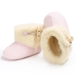 Macro view of pink baby winter snow boots featuring warm fleece lining and wooden toggle button.