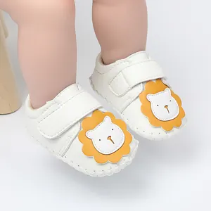 Gros plan de chaussures de marche pour bébé blanches avec un joli dessin de lion jaune.