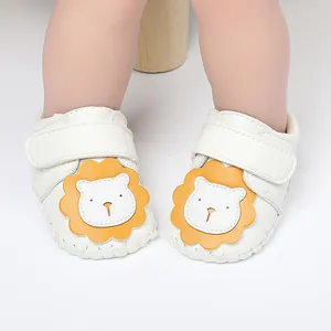 Vista detallada de zapatos de cuero blanco para bebé con un lindo diseño de león amarillo