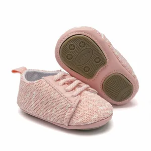 Detail view of pink knitted baby shoes showing non-slip rubber sole with baby text
