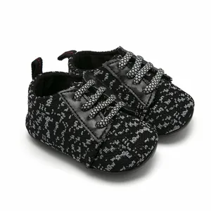 Detailed view of black and grey knitted infant sneakers featuring durable woven laces.