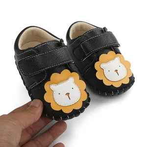 Détail de chaussures de marche pour bébé noires avec semelle antidérapante et motif lion