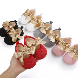 Vista detallada de zapatos de princesa para bebé con lazos de satén oro champán.