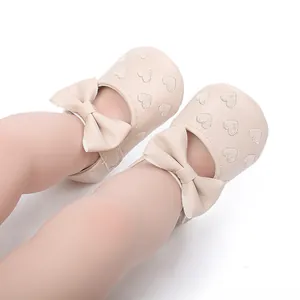 Nahaufnahme der niedlichen beigen Baby-Prinzessinnen-Lauflernschuhe mit Herzstickerei