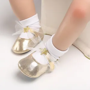 Nahaufnahme von goldfarbenen Baby-Prinzessin-Schuhen mit Netzschleife und Stern