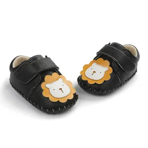 Gros plan sur les chaussures de bébé noires avec motif lion et semelles antidérapantes