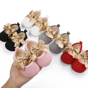 Vista detallada de los zapatos de princesa para bebé con grandes lazos dorados