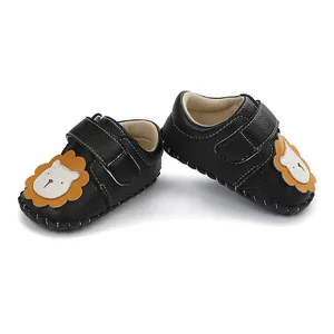 Vue détaillée de chaussures noires pour bébé avec visage de lion et bride velcro.