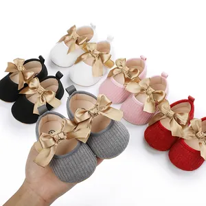 Detalle de zapatos de princesa para bebé con elegantes lazos dorados