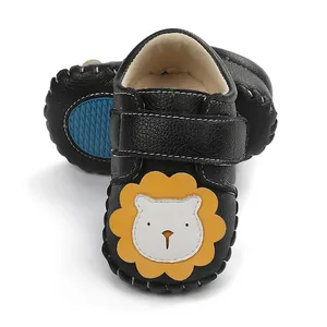 Gros plan détaillé de chaussures de marche pour bébé noires avec motif de lion jaune