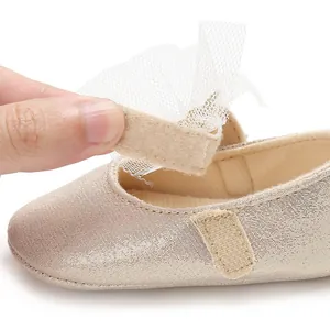 Detailaufnahme eines goldenen Baby-Prinzessin-Schuhs mit Tüllschleife und Klettverschluss