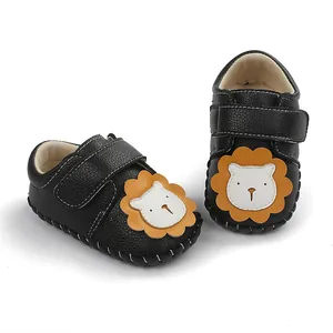 Gros plan de chaussures de marche pour bébé noires avec un motif de lion de dessin animé.