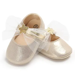 Nahaufnahme von goldenen Glitzer-Babyschuhen mit weißer Netzschleife und einem Stern