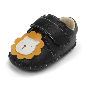 Gros plan de chaussure bébé en cuir noir avec un motif mignon de lion en dessin animé
