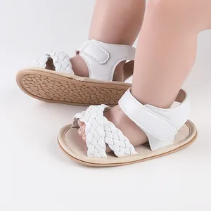 Close-up of white braided baby sandals with soft soles and velcro strap for infants.