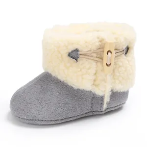 Vista lateral de botas de nieve para bebé de felpa gris y blanca con botón de madera