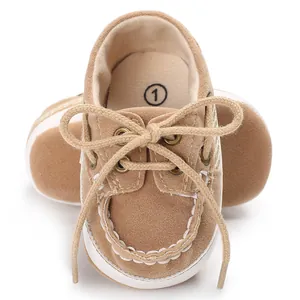 Nahaufnahme der braunen Wildleder-Babyschuhe mit weißen weichen Sohlen und Schnürsenkeln