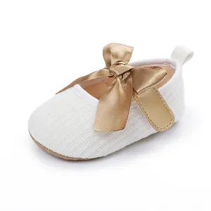 Primer plano de zapato blanco para bebé con un elegante lazo decorativo de satén dorado