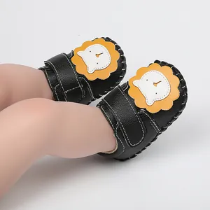 Gros plan de chaussures pour bébé noires avec motif lion mignon et semelles souples