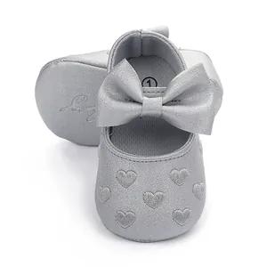 Detailansicht silberner Baby-Prinzessinenschuhe mit Schleife und Herzstickerei