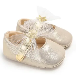 Nahaufnahme goldener Baby-Prinzessinenschuhe mit weißer Spitzenschleife und Sternen