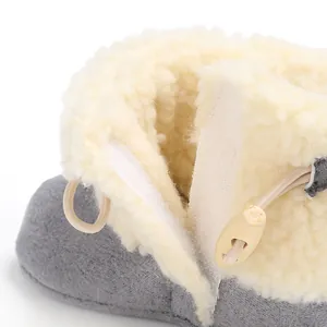 Close-up detail view of plush baby snow boot with Velcro closure and wooden button decoration.