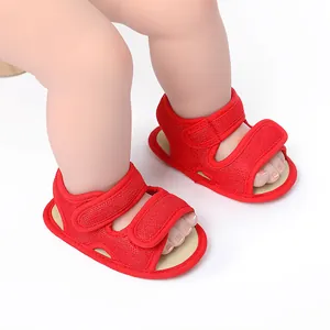 Close-up of red mesh baby sandals with secure Velcro straps shown on model doll feet