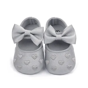 Detailansicht süßer silberner Baby-Prinzessinnenschuhe mit großer Schleife und Herzstickerei