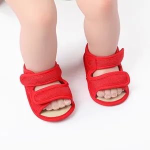 Close-up detail of red baby summer walking shoes with adjustable straps on baby feet