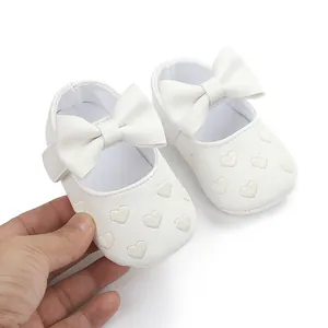 Close-up of white baby walking shoes with embroidered hearts and bows