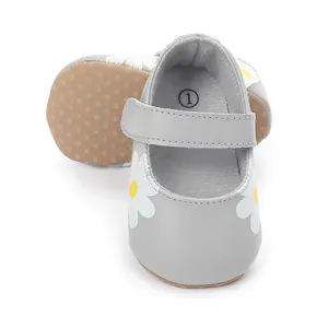 Close-up detail of grey baby walking shoes with white daisy print and a strap