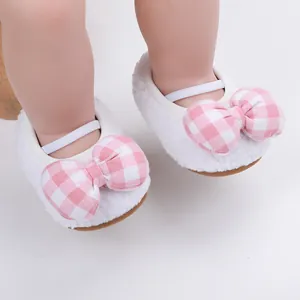 Dettaglio di scarpe primi passi bianche con fiocchi a quadretti rosa.