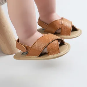 Brown leather baby pre-walker sandals with a soft sole and a cross strap design.