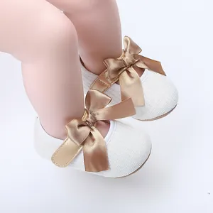 Primer plano detallado de zapatos blancos de princesa para bebé con lazo de raso dorado