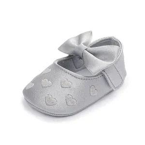 Nahaufnahme eines silbernen Baby-Prinzessinnenschuhs mit Schleife und Herz-Stickereien