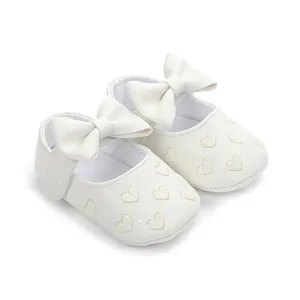Close-up of white baby walker shoes featuring heart patterns and decorative bows.