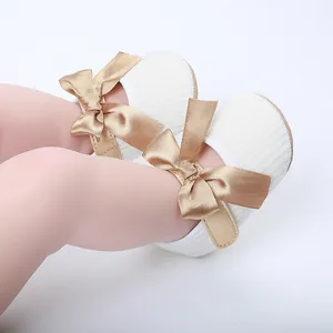 Vista detallada de zapatos blancos de princesa para bebé con elegantes lazos de satén.