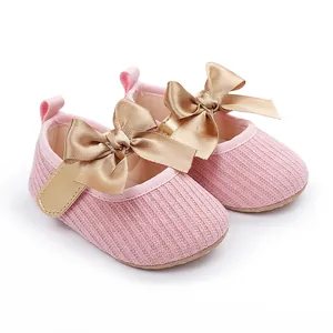 Primer plano detallado de zapatos de bebé rosas con textura y elegantes lazos de raso dorado